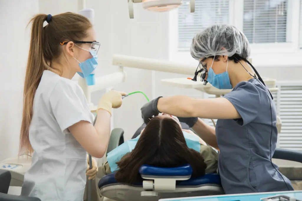 Orthodontic assistant helping dentist with dental procedure.