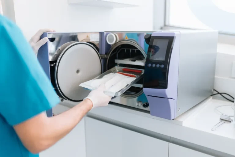 Dental assistant practicing infection control by sterilizing dental instruments.