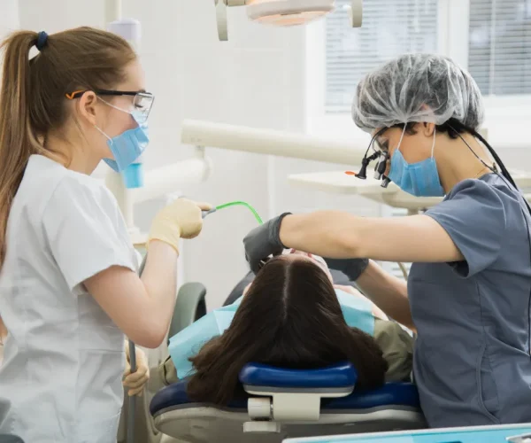 Orthodontic assistant helping dentist with dental procedure.