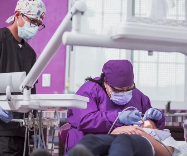 dentist and dental assistant wearing full PPE during a patient procedure.