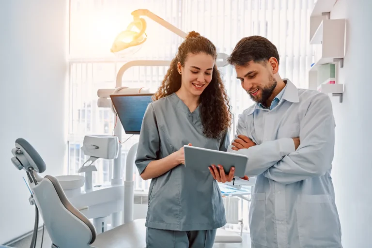 Dental assistant in scrubs collaborating with a dentist in a modern clinic.